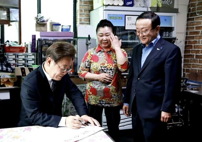 지난 6월 13일, 이재명 대통령이 김덕현 연천군수와 함께 연천군 청산면을 방문해 경기도 농촌기본소득 시범지역 소상공인과 담화를 나누며 방명록을 작성하고 있다.