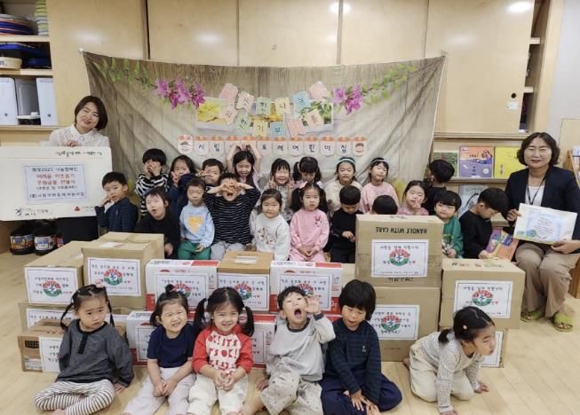 시립어반포레어린이집에서 김민경원장과 원아들이 함께 후원금품 전달식을 진행하고 있다.