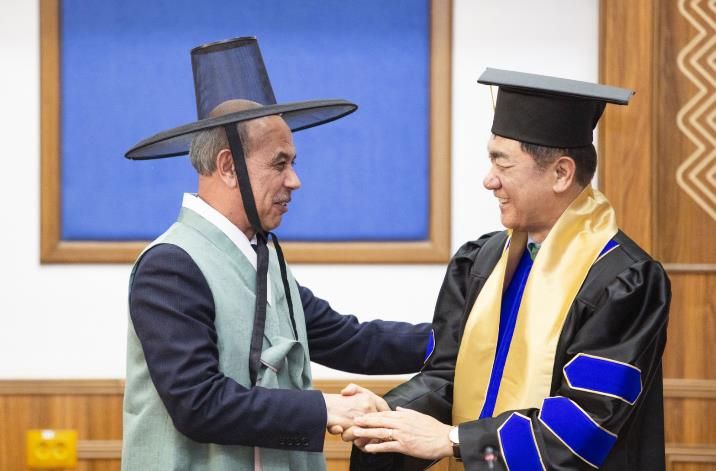 정장선 평택시장이 대학 명예교수로 임명된 가운데, 평택시가 선물한 한복을 입은 툴킨 테샤바예프 총장과 악수를 나누고 있다.