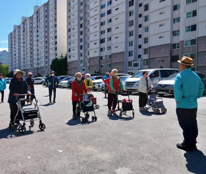 어르신들이 아파트 단지 앞에 모여 걷기 운동 시작 전 준비운동을 하고 있다